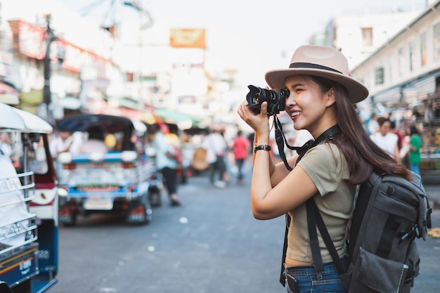 Side view of woman photographing on street in city