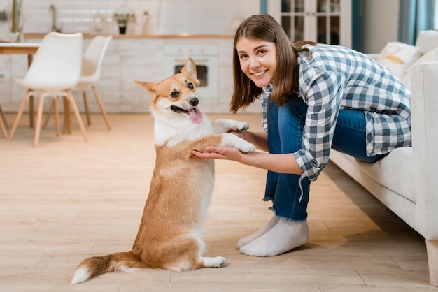 Vista laterale della donna che posa mentre tenendo le zampe del cane