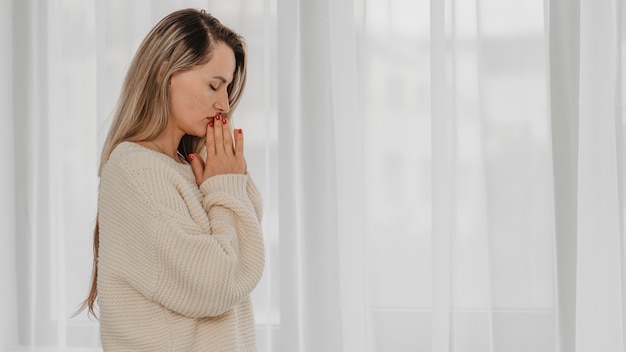 Foto vista laterale della donna che prega a casa con copia spazio