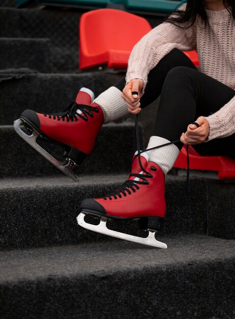 Photo side view woman putting on ice skates