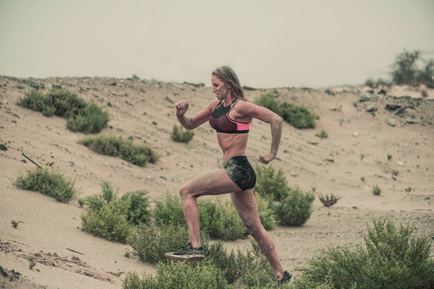 Foto vista laterale di una donna che corre sulla sabbia