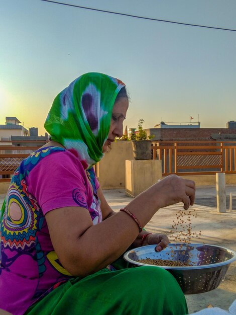 Foto vista laterale di una donna che setaccia il grano