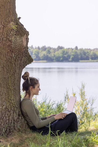 Foto vista laterale di una donna seduta vicino al lago