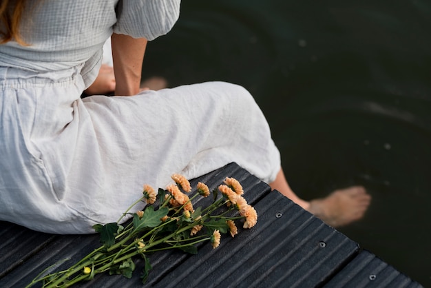 Foto donna di vista laterale che si siede in riva al lago