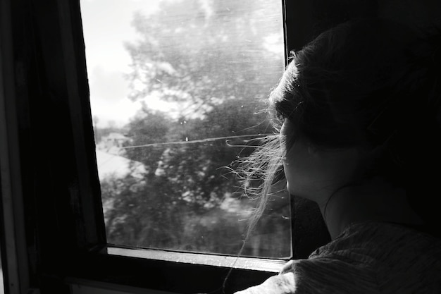 Photo side view of woman sitting by window while traveling in train