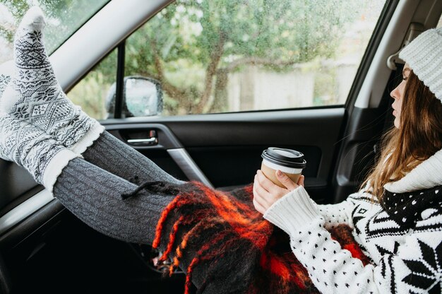 写真 一杯のコーヒーと車に座っている側面図の女性