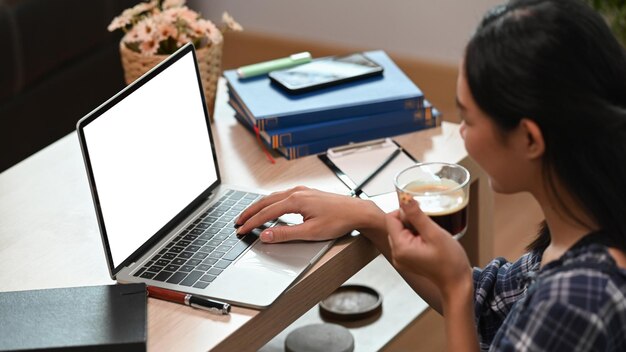 Side view woman sitting in living room and browsing internet with laptop