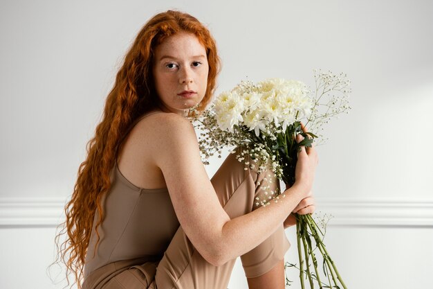 Foto vista laterale della donna seduta e in posa con fiori primaverili