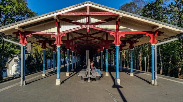 Foto vista laterale di una donna seduta sulla piattaforma della stazione ferroviaria