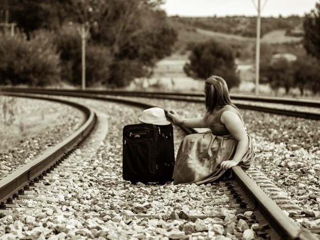 Foto vista laterale di una donna seduta sul binario ferroviario