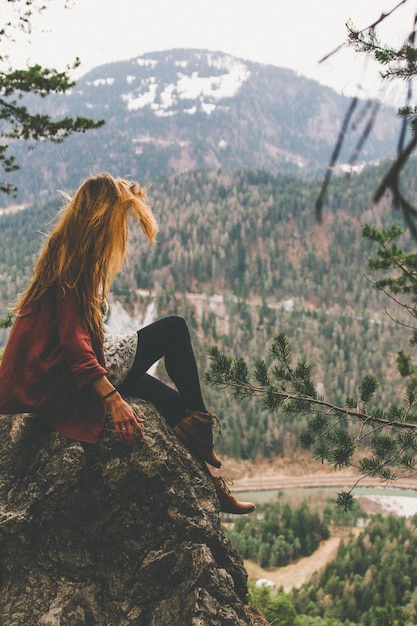 side view of woman sitting on rock