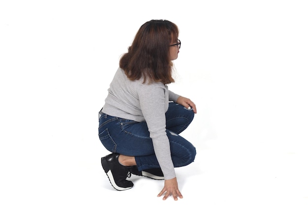 Side view of woman squatting on white background