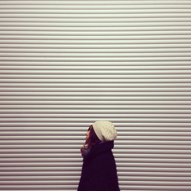 Side view of woman standing against closed shop