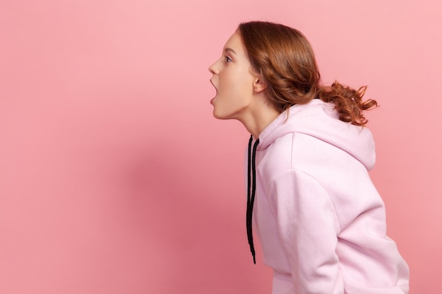 Photo side view of woman standing against pink background