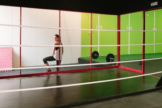 Photo side view of woman standing by chainlink fence