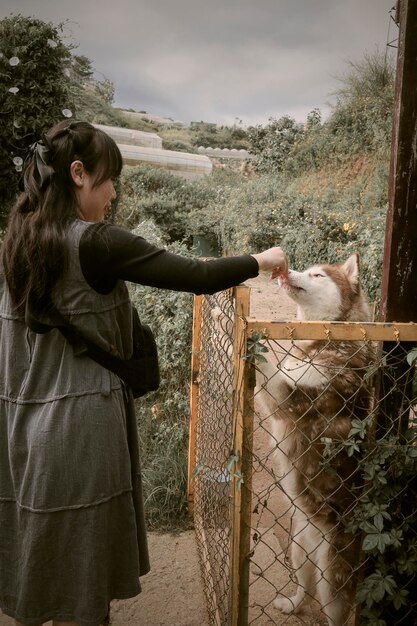 Foto vista laterale di una donna in piedi vicino alla recinzione