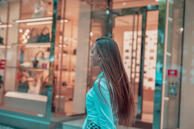 Photo side view of woman standing on footpath by store window