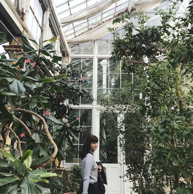 Photo side view of woman standing in greenhouse