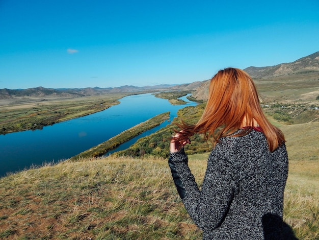 Side view of woman standing on mountain against clear sky