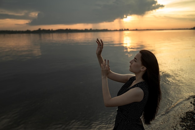 Foto vista laterale di una donna in piedi in acqua al tramonto