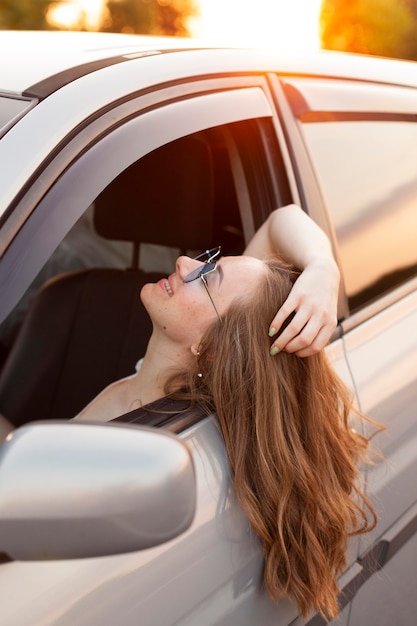 Foto vista laterale della donna che attacca la testa fuori dall'auto