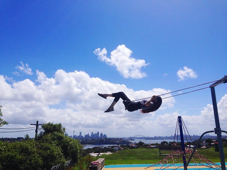 Photo side view of woman swinging against blue sky