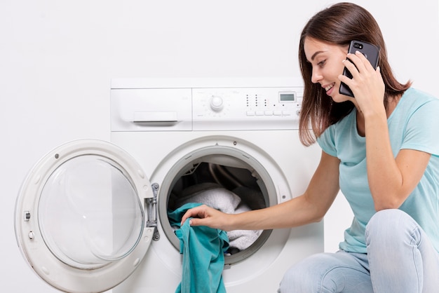 Photo side view woman talking on the phone in laundry room