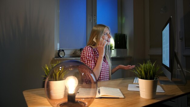 Photo side view of woman talking over smart phone at home