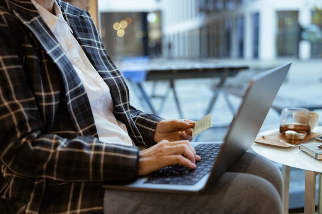 Foto vista laterale della donna che digita sulla tastiera mentre inserisce i dettagli della carta di credito per effettuare acquisti