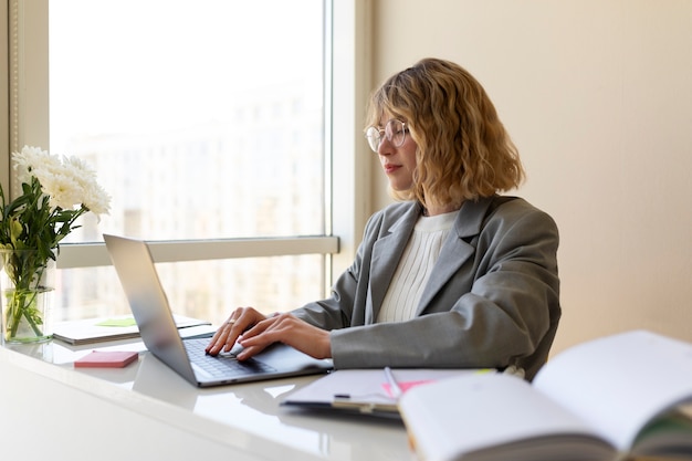 Donna di vista laterale che scrive sul computer portatile