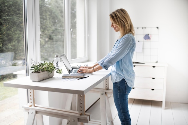 Photo side view of woman using laptop at home