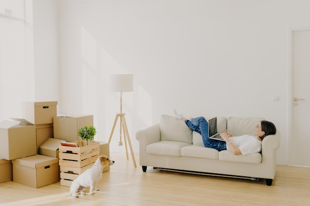 Photo side view of woman using laptop at new home