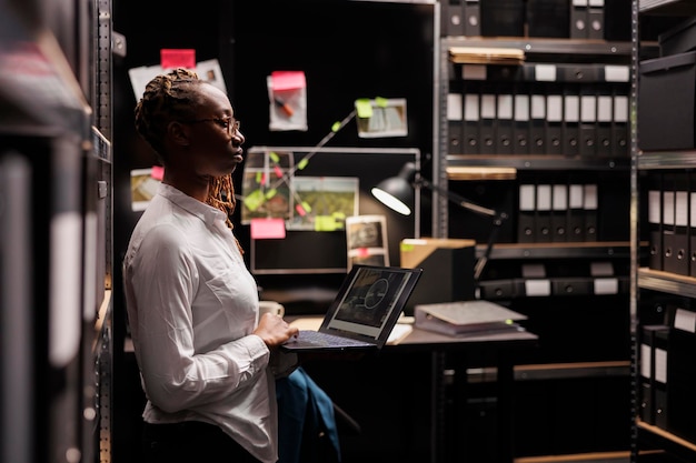 Side view of woman using laptop while standing in library