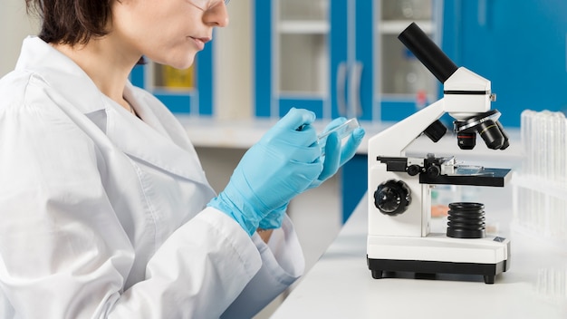 Photo side view woman using a microscope