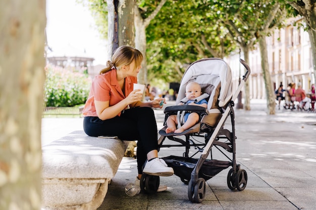 Foto vista laterale di una donna che usa il telefono cellulare mentre è seduta in un parco