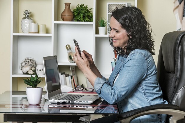 Side view of woman using phone while sitting on table