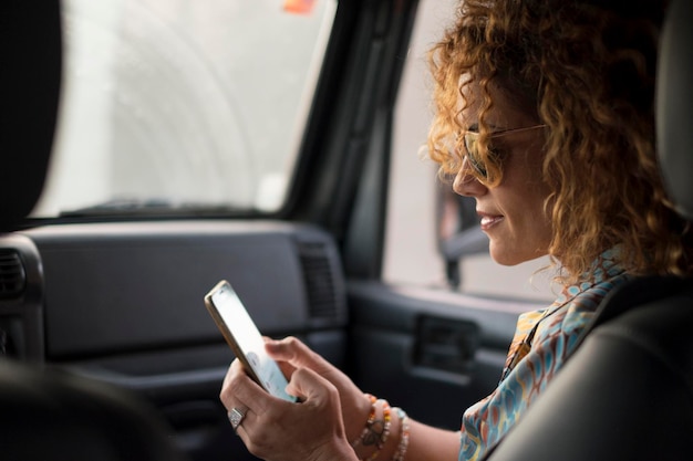 Foto vista laterale di una donna che usa lo smartphone in auto