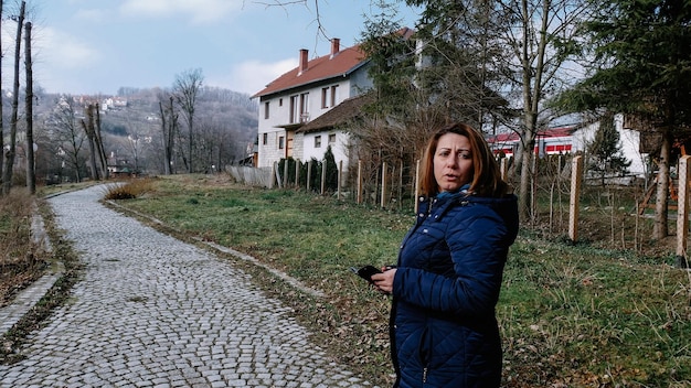 Foto vista laterale di una donna che usa lo smartphone mentre si trova sul marciapiede