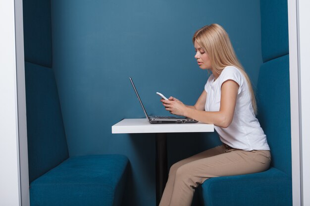 Side view woman using a smartphone while sitting in a modern workspace