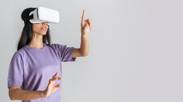 Vista laterale della donna che utilizza le cuffie da realtà virtuale con lo spazio della copia