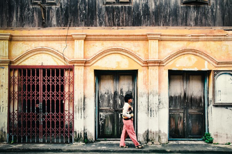 फोटो side view of woman walking on footpath by building