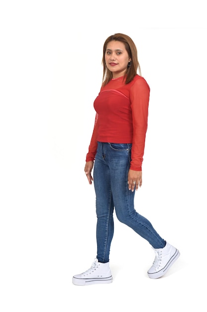 Photo side view of a woman walking and looking at camera on white background