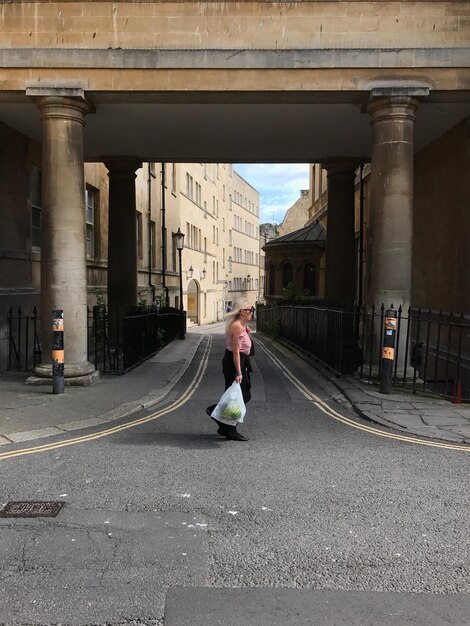 Foto vista laterale di una donna che cammina sulla strada tra gli edifici