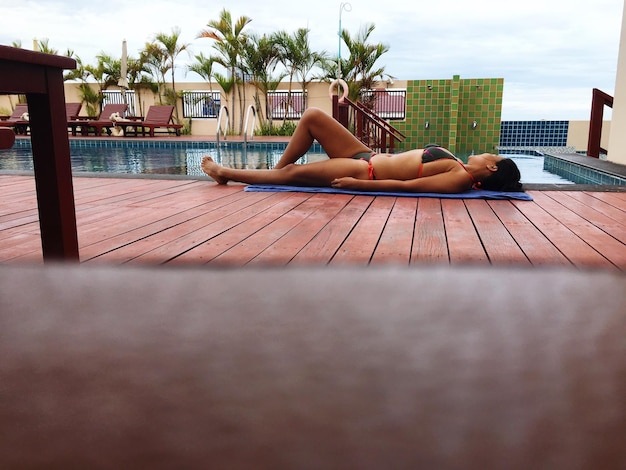 Photo side view of woman wearing bikini while lying at poolside