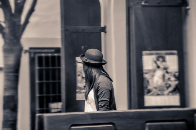side view of woman wearing hat against building