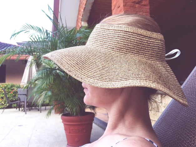 Photo side view of woman wearing hat sitting against house