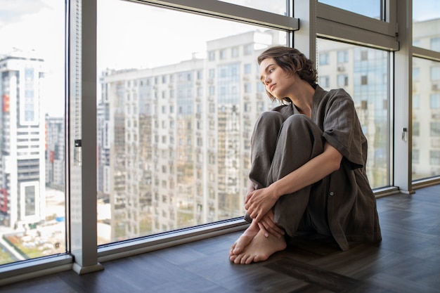 Photo side view woman with anxiety sitting on floor