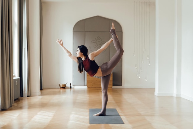 side view of woman with arms raised doing yoga on floor