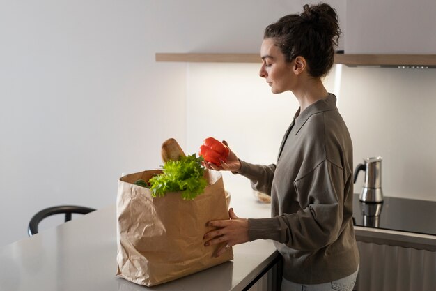 Side view woman with groceries at home