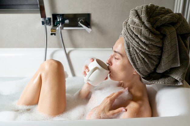 Photo side view woman with mug in bathtub